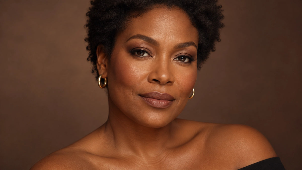 Confident Black woman in her forties with a softly blurred, healthy velvet complexion and warm fall makeup